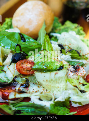 Salade d'été fraîches avec tomates cerises, roquette, jeunes épinards, laitue romaine et dans une assiette sur fond de bois blanc, sélective Banque D'Images