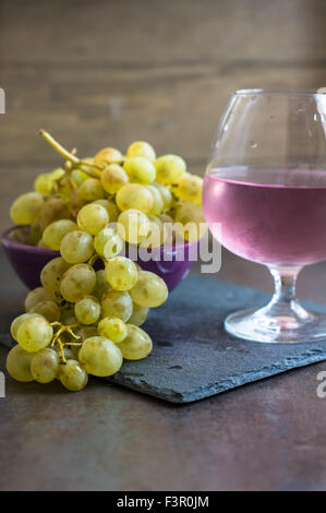 Verre de vin rose et raisins mûrs sur fond vintage. Selective focus Banque D'Images