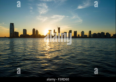 Silhouette au coucher du soleil sur les toits de la ville de Jersey City et Hoboken, New Jersey de partout les eaux de la rivière Hudson à New York City Banque D'Images