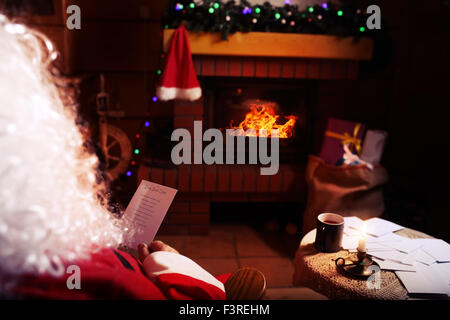 Le Père Noël lit les lettres des enfants dans leur chalet d'hiver Banque D'Images