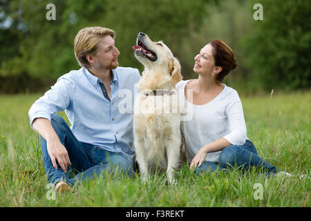 Couple sitting on meadow avec Labrador Banque D'Images