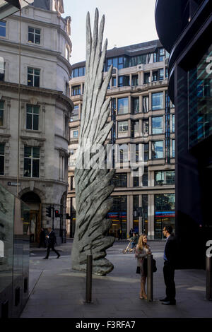 City workers talk sous un artwork d'une aile de bronze à l'heure du déjeuner dans le quartier financier de Londres. Comme la lumière se reflète sur les immeubles de bureaux à proximité, la foule à l'heure du déjeuner devant ce géant des illustrations sur leur façon de réunions et sandwicheries. Les dix mètres de haut est la sculpture en bronze par le président de la Royal Academy of Arts, Christopher Le Brun, commandé par Hammerson en 2009. Elle est appelée 'La Ville' de l'aile et a été jeté par Morris Singer, fondateurs de l'art réputé pour être la plus ancienne fonderie d'art dans le monde. Banque D'Images