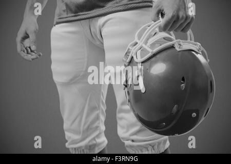 Image composite d'un joueur de football américain en tenant son casque sur sa main Banque D'Images
