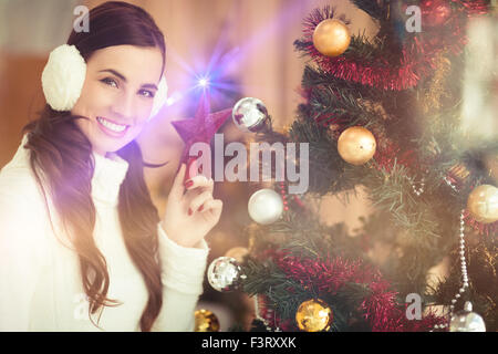 Smiling brunette holding star près d'un arbre de Noël Banque D'Images