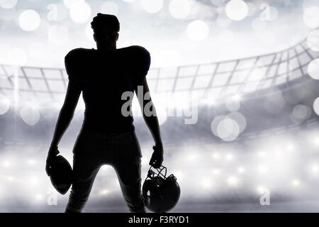 Image composite de silhouette american football player holding ball et le casque Banque D'Images