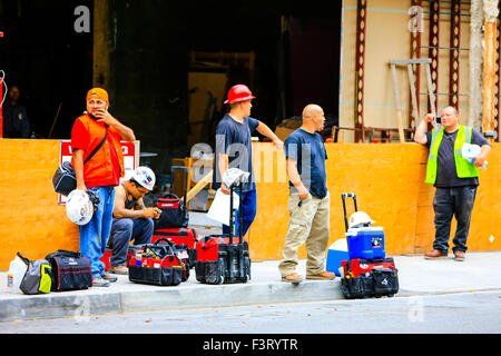 Les travailleurs de la construction d'attendre au bord du trottoir pour la balade hors de Los Angeles Californie Banque D'Images