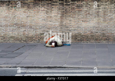 Un mendiant sur le trottoir à l'extérieur des murs des musées du Vatican. Banque D'Images