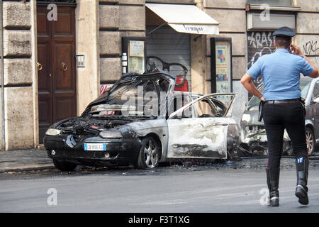 Un policier s'occupant d'une voiture brûlée dans une rue de Rome. Banque D'Images