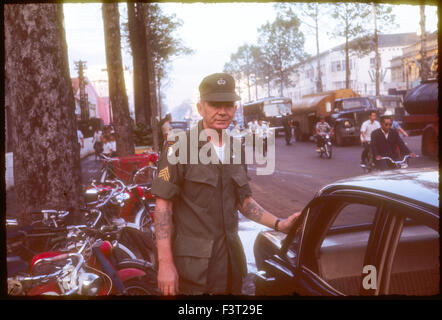 Le sergent portant un patch de la 101st Airborne Division, et sauter les ailes, pour indiquer un tour précédent, se trouve à proximité d'une rue animée à Saigon pendant la guerre du Vietnam. Banque D'Images