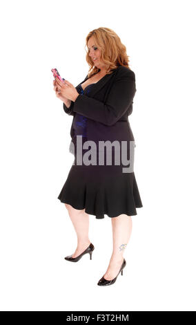 Une blonde grande taille femme d'affaires dans un blouson noir portant sur son téléphone cellulaire, debout de profil isolées pour fond blanc. Banque D'Images