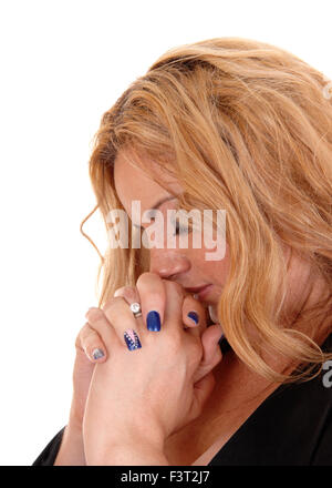 Une jeune blonde grande taille Femme de profil avec ses mains jointes, priant, isolée pour fond blanc. Banque D'Images
