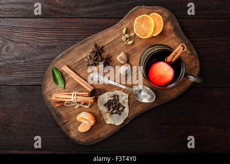 Verre de vin chaud (poinçon) Porte-verre en servi sur plaque en bois avec des épices sur la table en bois sombre. Vue d'en haut Banque D'Images