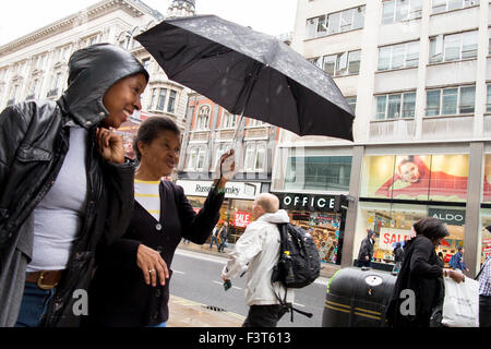 Un jour de pluie à Londres, les gens se trouvent à l'extérieur du shopping sur Oxford Street Banque D'Images