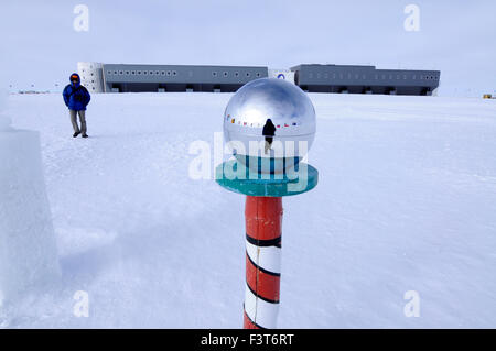 Un scientifique au Pôle sud avec station Amundsen-Scott South Pole Gare derrière le miroir à la pôle de cérémonie Banque D'Images