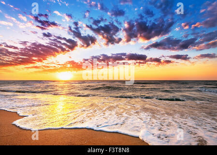 Plage de l'océan brillant le lever du soleil. Banque D'Images