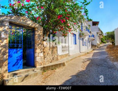 Une ruelle pittoresque sur l'île grecque Spetses. La traditionnelle portes bleues et des murs blancs ainsi que l'usine de bougainvilliers o Banque D'Images