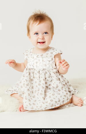 Cute little girl smiling sitting on le cacher. Banque D'Images