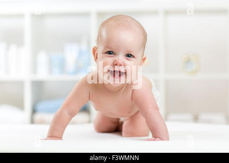 Heureux bébé enfant ramper sur bed and smiling Banque D'Images