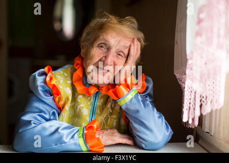 Femme âgée en vêtements ethniques, un portrait assis à la table. Banque D'Images