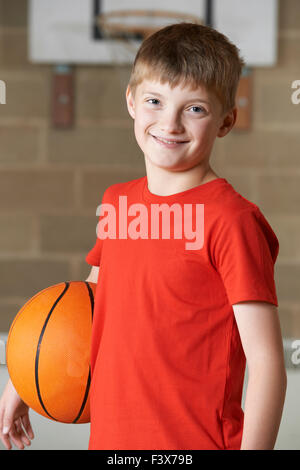 Portrait Of Boy Holding Basket-ball au gymnase de l'école Banque D'Images