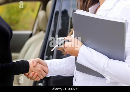 Saleslady vendre une voiture et shaking hands Banque D'Images