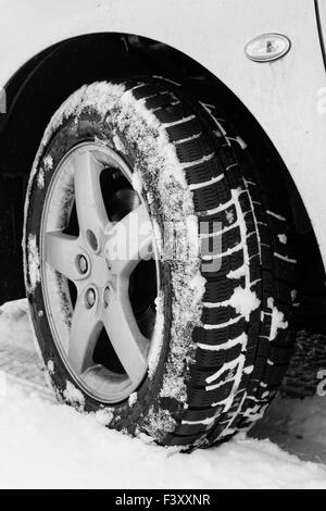 Close up d'un des pneus de voitures sur une route enneigée Banque D'Images