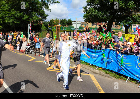 Ramsgate, Royaume-Uni. Jeux Olympiques de 2012. Le flambeau en cours le long de la route de Londres et passé des centaines d'enfants de l'école d'encouragement recueillies étant les bannières bleues. Banque D'Images