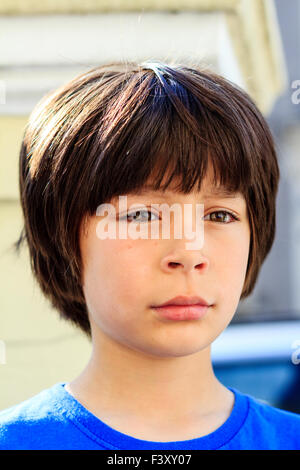 Brown haired caucasien enfant, garçon, 9-10 ans, debout en plein soleil, à la colère et larmes, tête et épaules. Se tourne vers l'avenir. En face. Banque D'Images