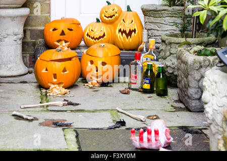 Porte avec halloween pumkins, taillées dans des os en plastique, bouteilles vides et divers autres éléments connexes à l'extérieur blanc porte avant. La journée. Banque D'Images