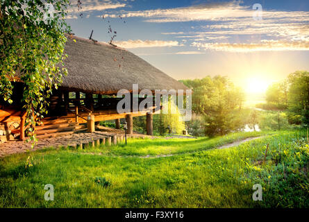 Maison de log près du lac au coucher du soleil Banque D'Images