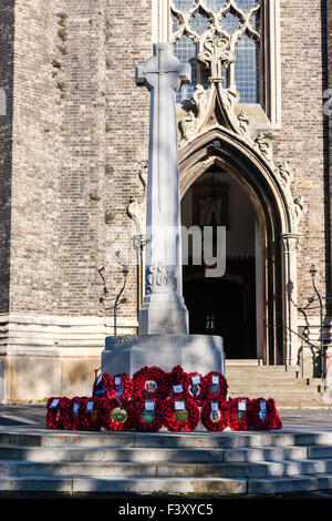 Dimanche du souvenir en Angleterre. Cénotaphe de la guerre avec l'affichage des couronnes fixées à la base du pavot. Derrière l'église est porte principale. Banque D'Images