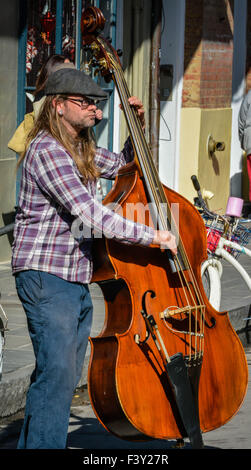 Musicien de rue portant un capuchon plat joue un stand up bass sur une rue bondée dans le quartier français de New Orleans, LA Banque D'Images