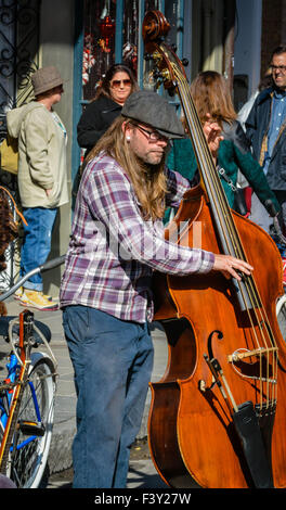 Musicien de rue portant un capuchon plat joue un stand up bass sur une rue bondée dans le quartier français de New Orleans, LA Banque D'Images