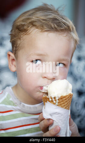 Cute little boy eating an ice cream cone Banque D'Images