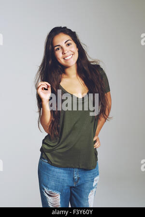 Jolie jolie jeune femme avec un sourire chaleureux en haillons portant des jeans et une designer occasionnels t-shirt standing looking at Banque D'Images