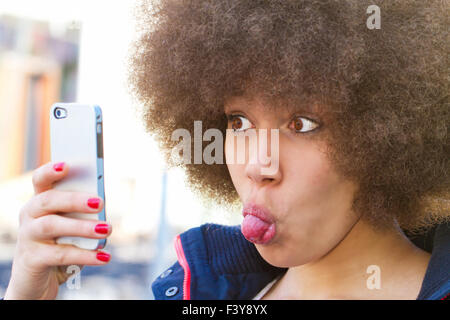 Jeune femme avec coupe de cheveux afro makin un drôle de self portrait Banque D'Images