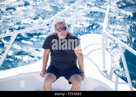 Homme assis sur la proue d'un bateau Banque D'Images