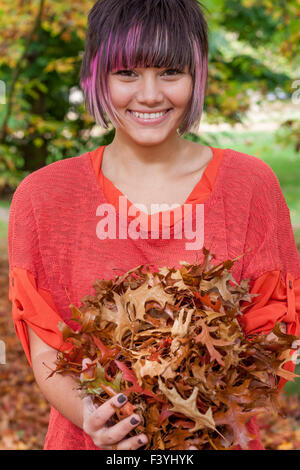 Londres, Royaume-Uni. 13 octobre, 2015. Une jeune femme heureuse et smiling holding une collection de feuilles d'automne dans la région de Hyde Park Crédit : Guy Josse/Alamy Live News Banque D'Images