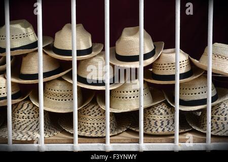 Les chapeaux de paille à vendre empilés derrière la fenêtre grill dans une rue de Trinidad, Cuba Banque D'Images