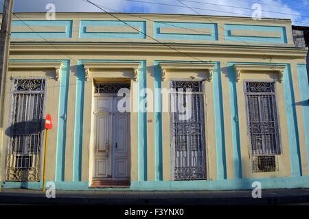 La façade jaune et turquoise pastel de vieux bâtiment colonial, Santa Clara, Cuba avec windows en cage, porte blanche et volets Banque D'Images