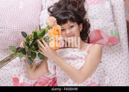 Girl in bed holding a bouquet of roses Banque D'Images