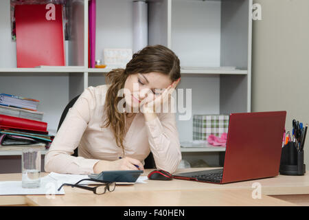 Fille de dormir sur un lieu de travail à l'office de tourisme Banque D'Images