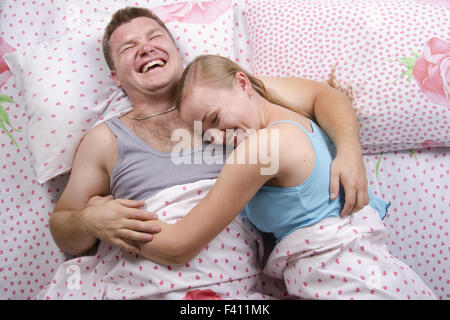 Young couple Lying in Bed et rit Banque D'Images