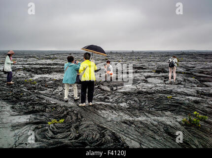 Les touristes japonais visiter un paysage pluvieux stérile de roche de lave champs, Hawai'i Volcanoes National Park, Big Island, Hawaii, USA Banque D'Images