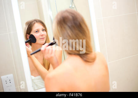 Jeune femme appliquant le maquillage dans la salle de bains Banque D'Images