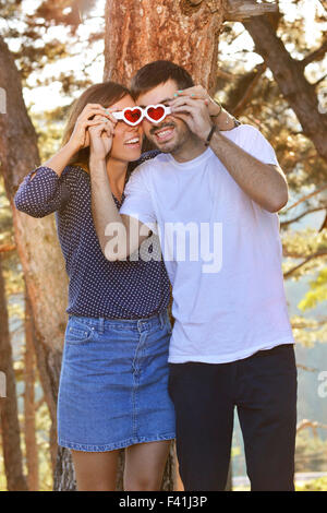 Couple heureux dans le parc à deux pas des lunettes en forme de coeur Banque D'Images