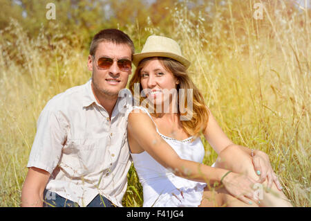 Couple assis sur le terrain lors d'une journée ensoleillée Banque D'Images