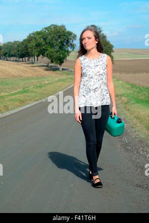 Jeune brunette avec de l'essence peut marcher on country road, Krageholm, Skåne, sud de la Suède Banque D'Images