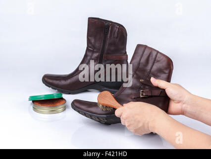 La main de femme boot polissage avec brosse à chaussure sur fond blanc Banque D'Images