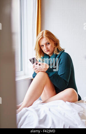 Femme regardant furtivement son téléphone alors qu'il n'y a pas de partenaire Banque D'Images